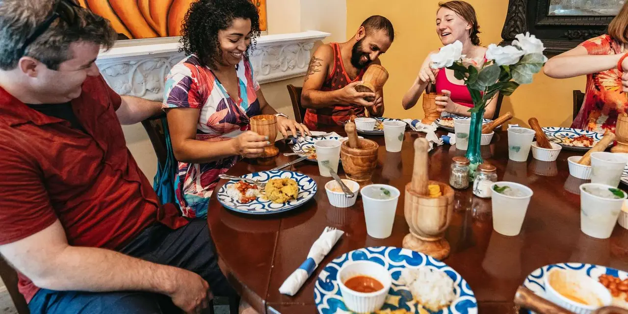 Friends sharing plates of food around a round wooden table