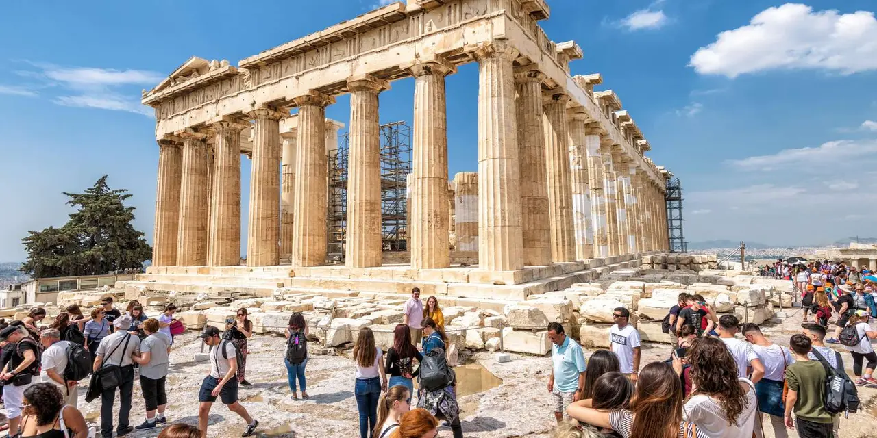 The Parthenon's columns, partly in scaffolding, with visitors crossing the marble plateau in front