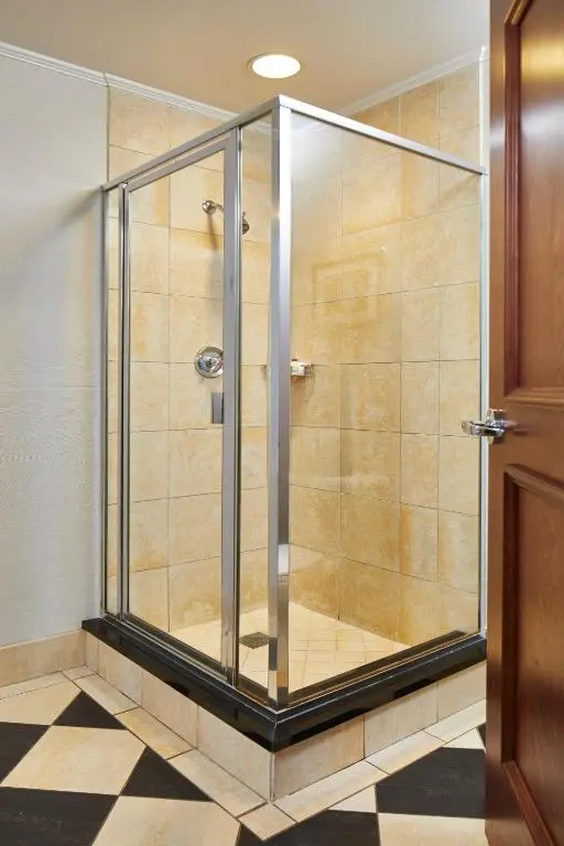 A glass-walled shower with stone tiles and a black-and-white checkered floor at the Battle House
