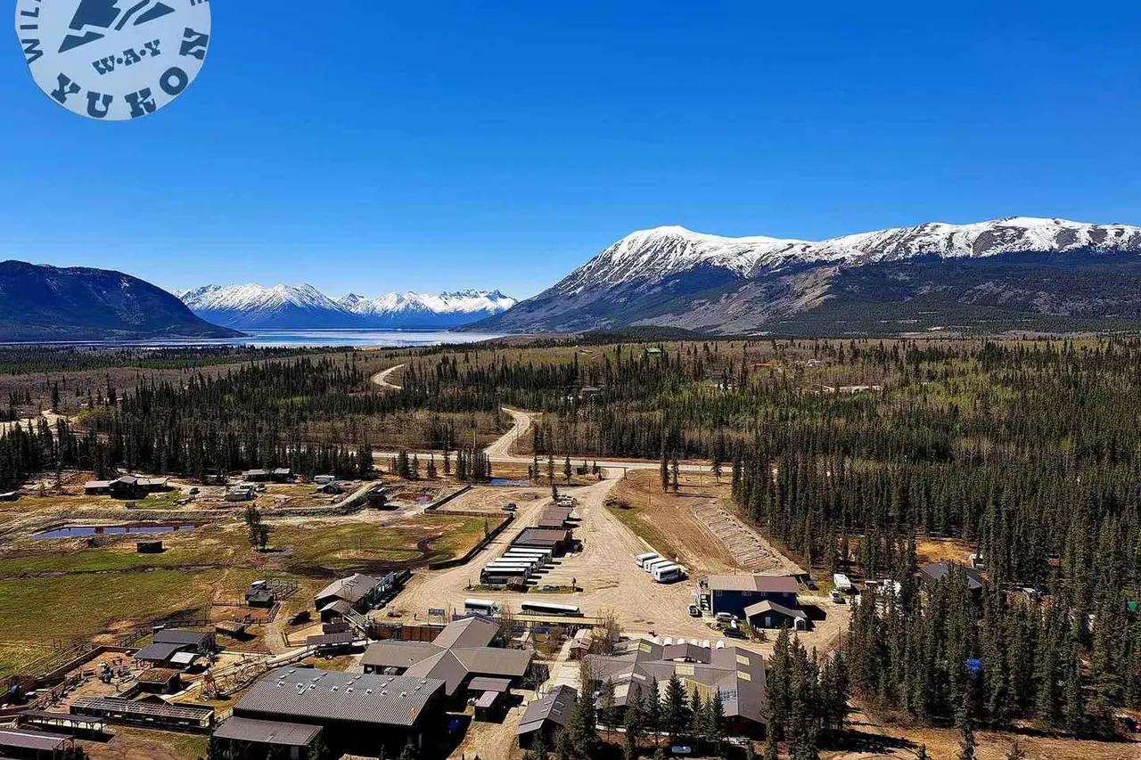 An aerial view of a Yukon visitor complex with a lake and snowy mountains behind