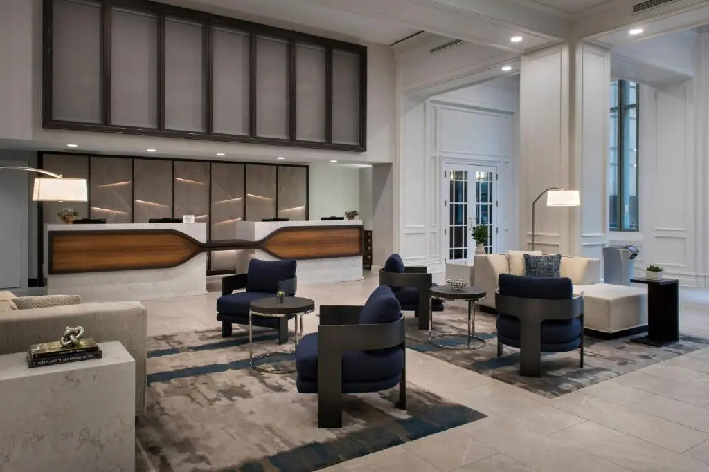 The lobby of the Norfolk Waterside Marriott, with a wood-and-stone front desk, navy armchairs and tall white-paneled doors
