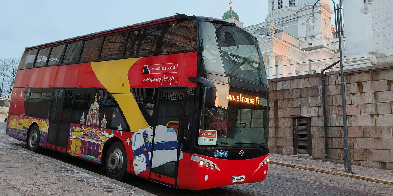 A red and yellow double-decker sightseeing bus on a cobbled street with the pale walls of Helsinki Cathedral rising behind it