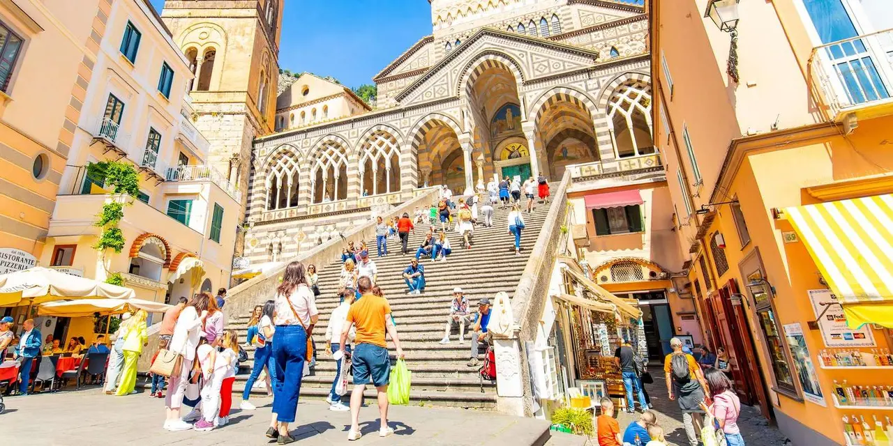 Visitors on the wide stone steps leading up to Amalfi Cathedral's striped arcaded façade