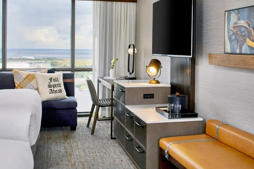 A Renaissance Riverview Plaza room with a blue sofa, desk and a window over the Mobile River