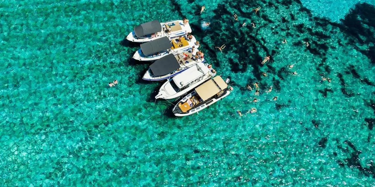 Several boats moored side by side in turquoise water over a pale seabed, seen from above