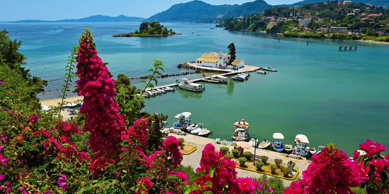 Vlacherna monastery and Mouse Island in a green bay seen from Kanoni, with pink bougainvillea in front