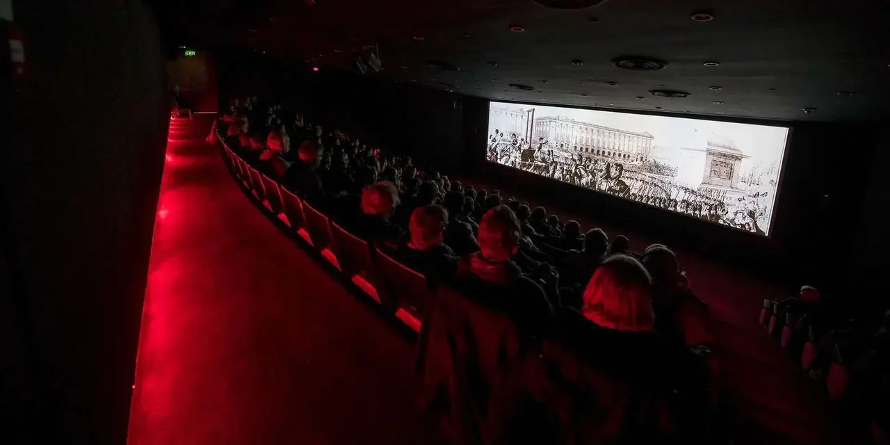 The darkened theatre of the Malta Experience, red seats facing a wide panoramic screen