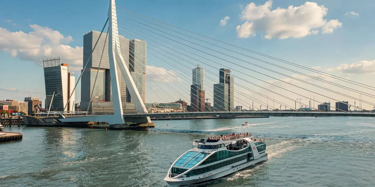 A white and glass Spido harbour cruise boat with passengers on its upper deck crossing the river in front of the Erasmus Bridge and De Rotterdam under a blue sky