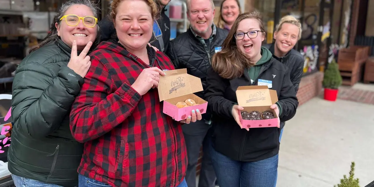 Smiling guests holding pink boxes of fresh donuts on a Portland food tour