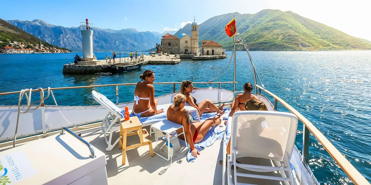 Passengers lounging on a catamaran deck with the island church and lighthouse behind them