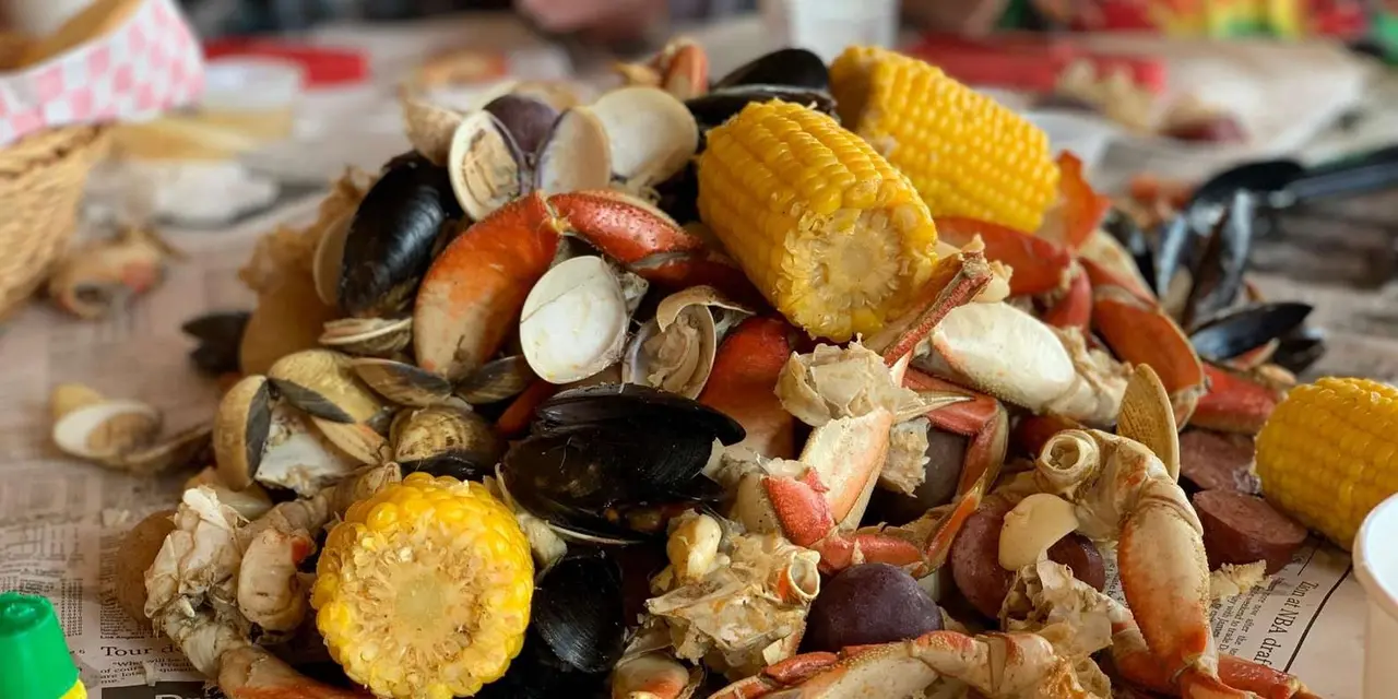 A seafood boil spread out on a table: corn, mussels, clams and crab