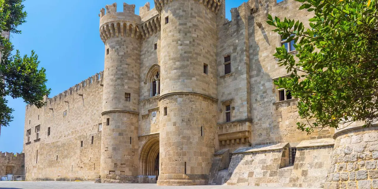 The Palace of the Grand Master's round stone towers and crenellated walls against a clear blue sky