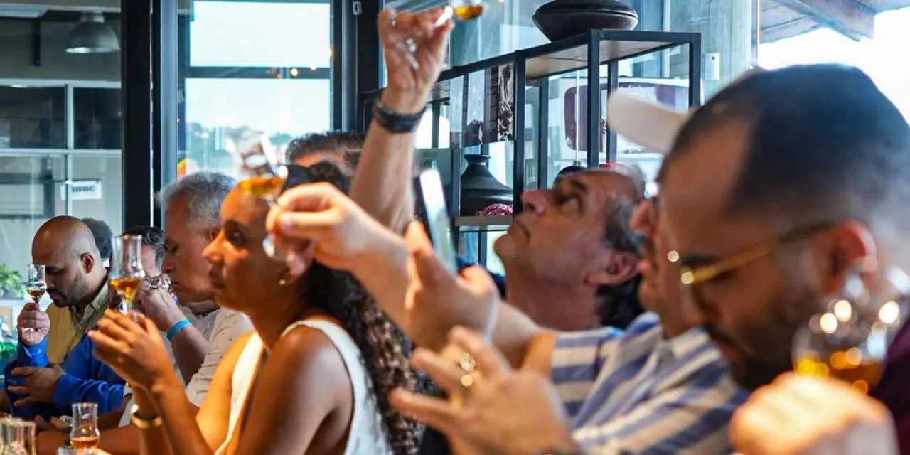 Guests at a bar laughing and tasting from small glasses
