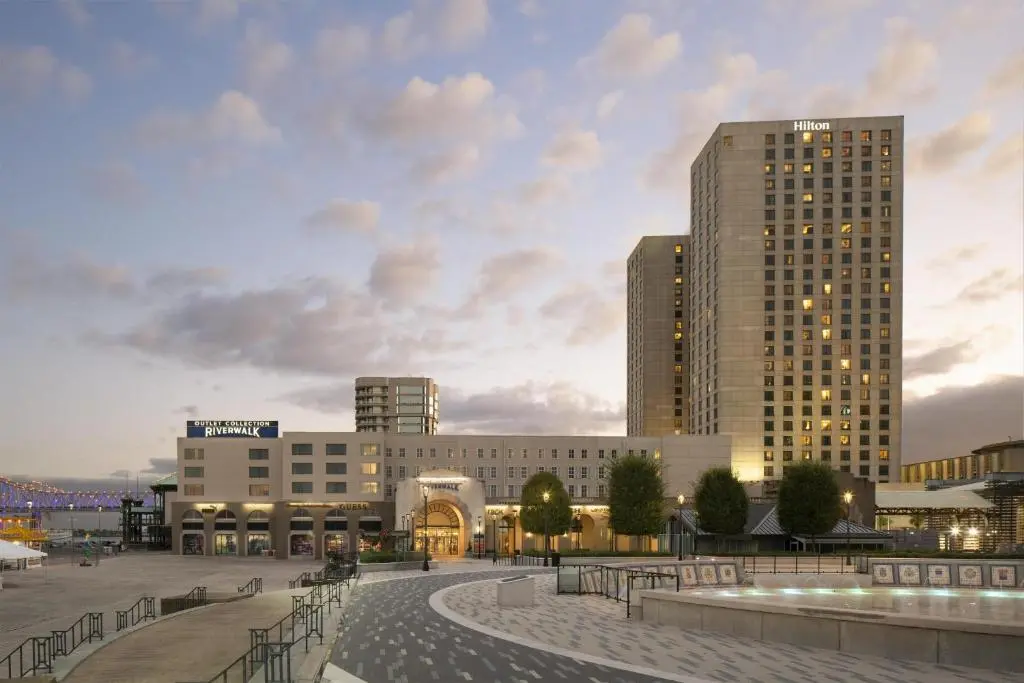 The Hilton New Orleans Riverside's tower beside the Riverwalk outlet building and plaza at dusk