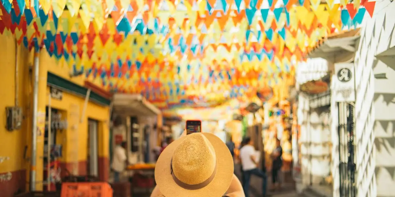 A woman in a straw hat looking down a colonial street hung with colourful bunting