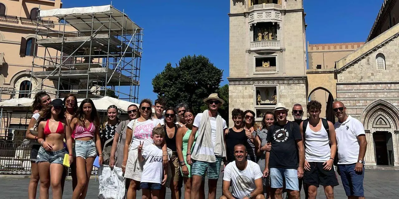 A tour group posing in summer clothes in front of Taormina's cathedral