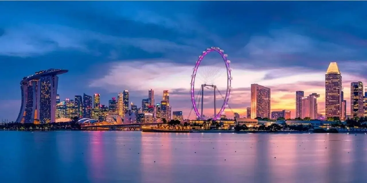 The Singapore Flyer lit pink at dusk beside Marina Bay Sands and the city skyline across the water