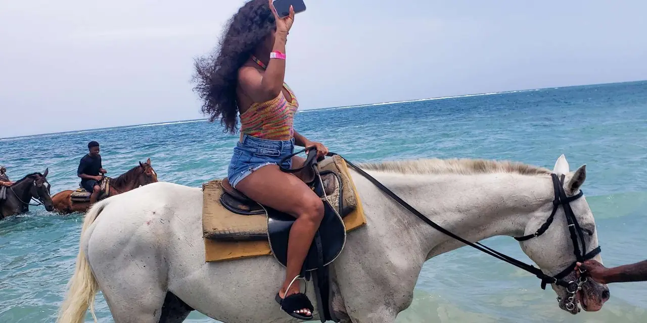 A woman riding a white horse beside the sea