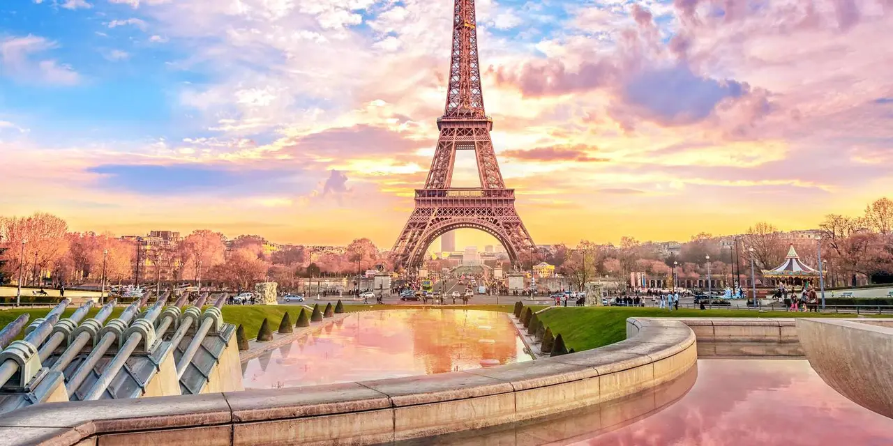 The Eiffel Tower at sunset above reflecting fountains and autumn trees in Paris