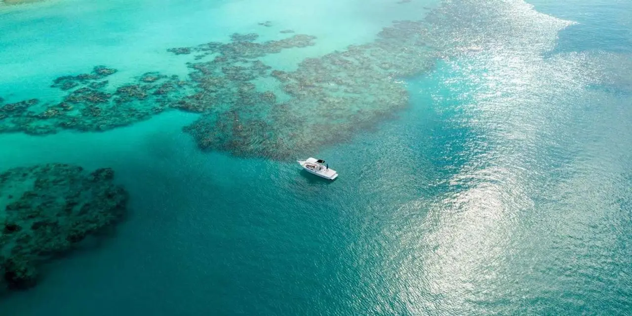 Aerial view of a boat anchored above a shallow reef in clear turquoise water
