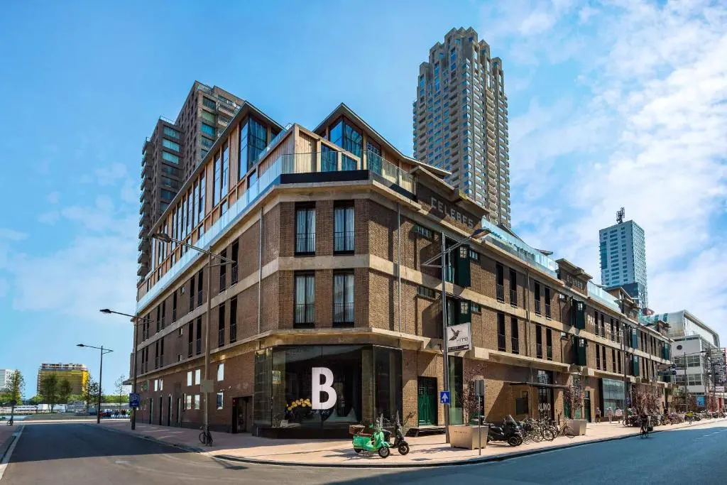 Room Mate Bruno, a brick former warehouse with a glass corner entrance on Wilhelminakade, with a tall apartment tower rising behind it