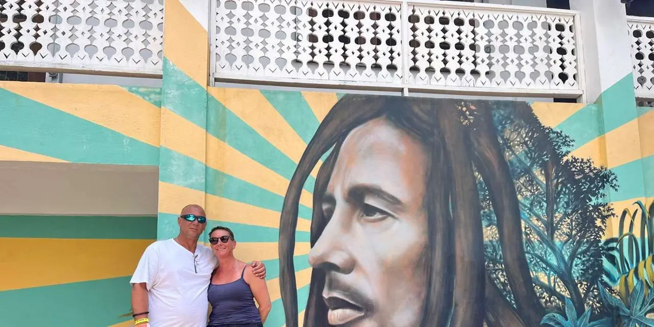 A couple posing in front of a large Bob Marley mural