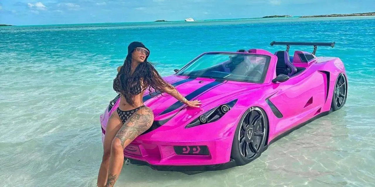 A woman posing beside a pink jet car on shallow turquoise water