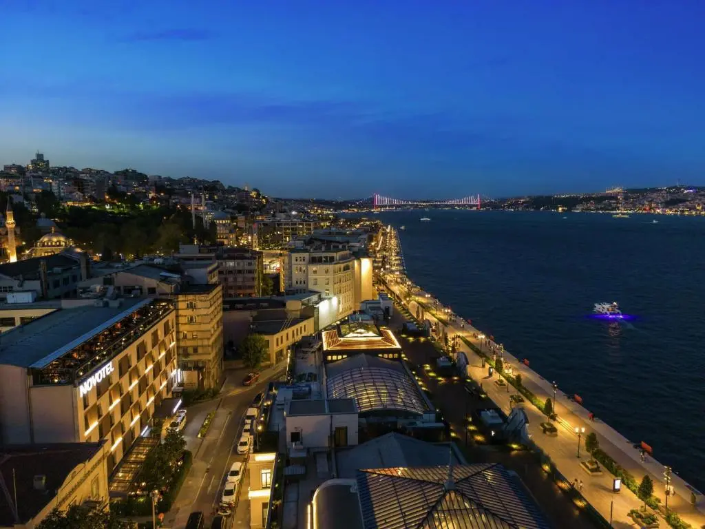 Night view from Novotel Istanbul Bosphorus over the lit Galataport waterfront and the Bosphorus, with the Bosphorus Bridge in the distance