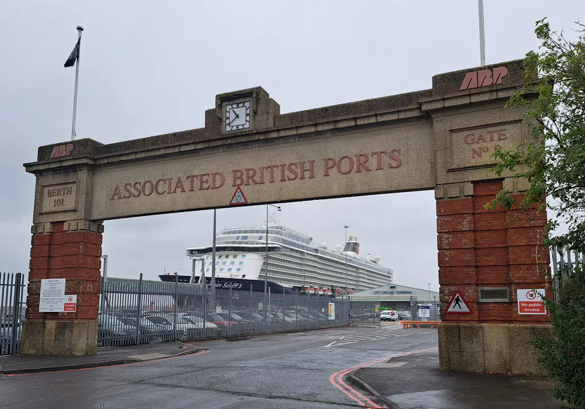 The red-brick Associated British Ports gate at Southampton's Berth 101, with a large white cruise ship docked behind it at the City Cruise Terminal on an overcast day
