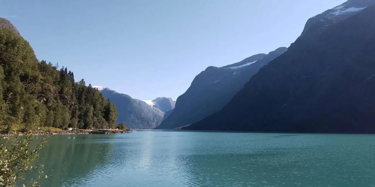 Calm lake water between steep dark mountains under a clear sky