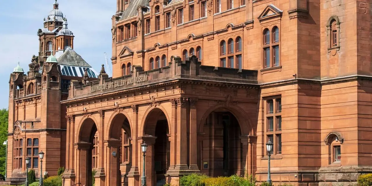 Kelvingrove Art Gallery's ornate red sandstone towers and arched entrance under a blue sky