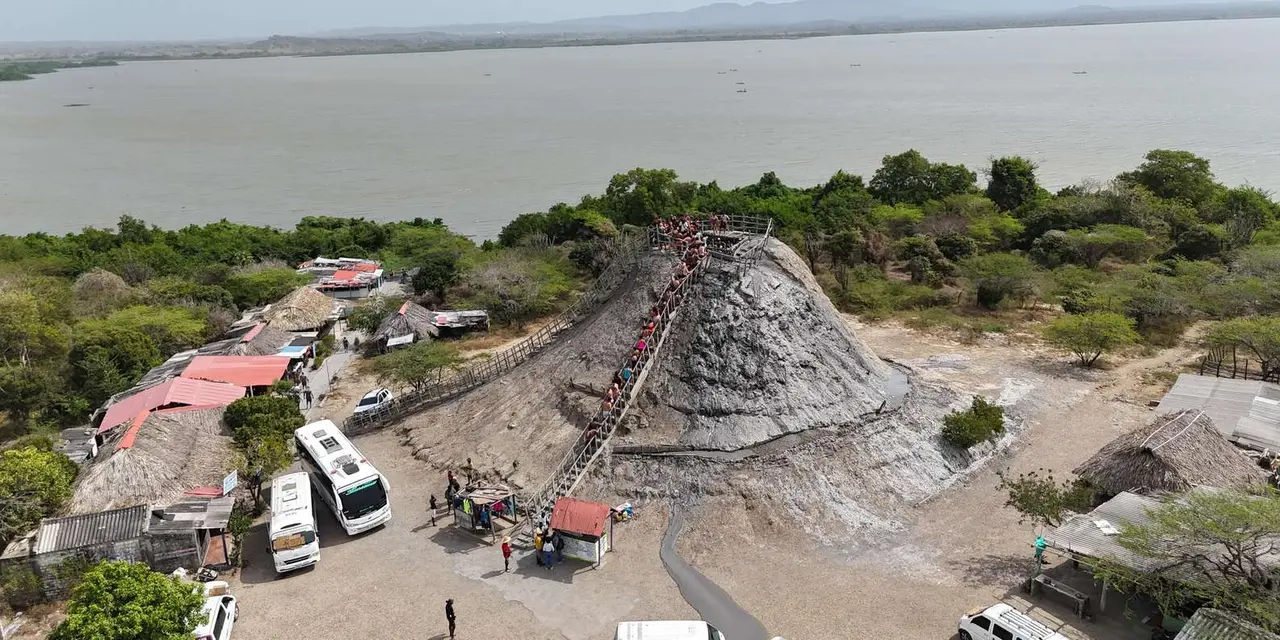 The grey cone of the Totumo mud volcano with a wooden stairway up its side, surrounded by trees