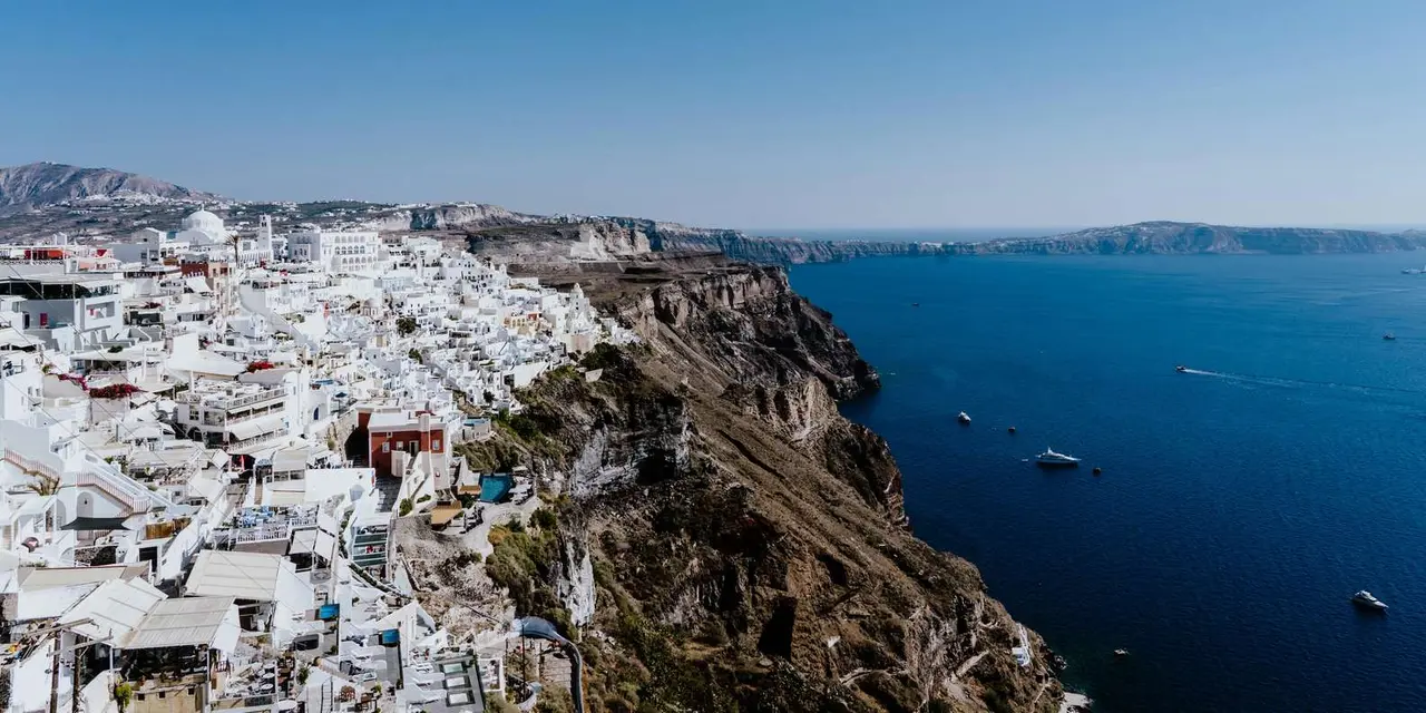 The whitewashed town of Fira along the caldera cliff, with deep blue sea to the right