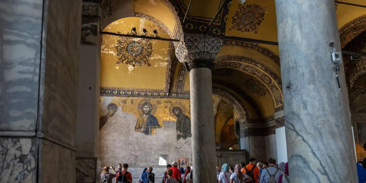 Visitors crowded under a Byzantine mosaic and marble columns inside Hagia Sophia