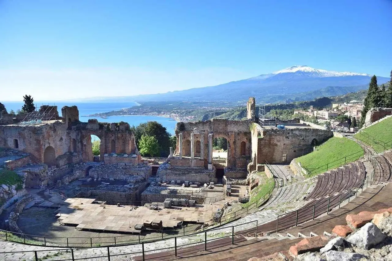 Taormina's ancient theatre ruins with the sea and snow-capped Mount Etna behind