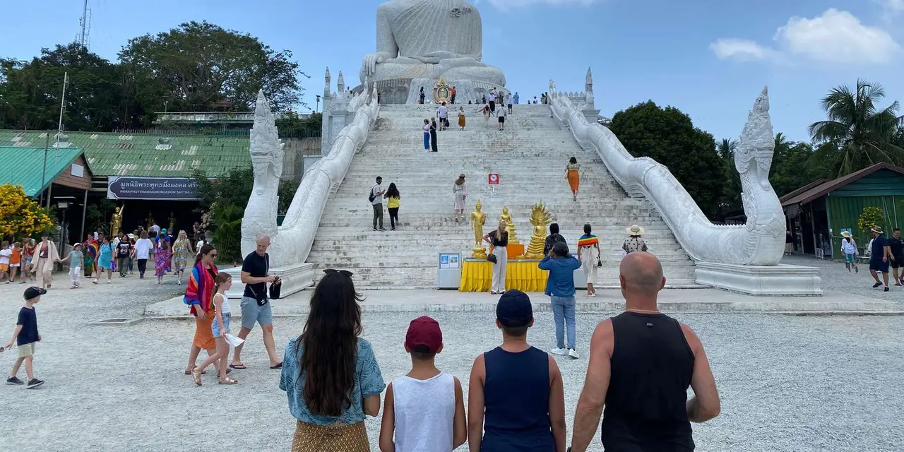 The white marble Big Buddha at the top of a broad staircase, with visitors on the terrace below