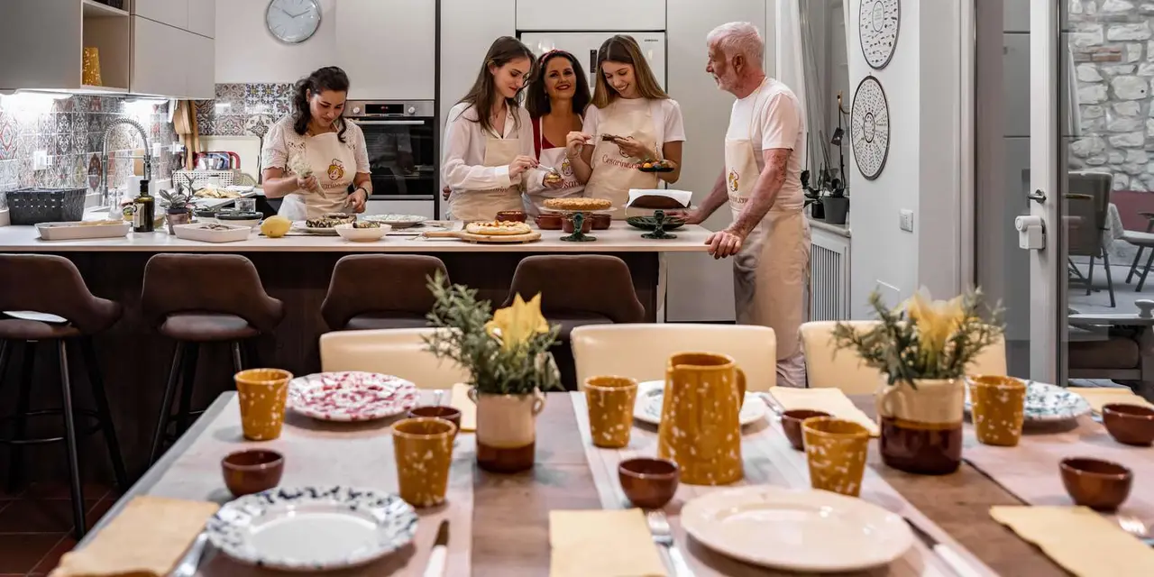 Guests and their host cooking together around a bright kitchen island
