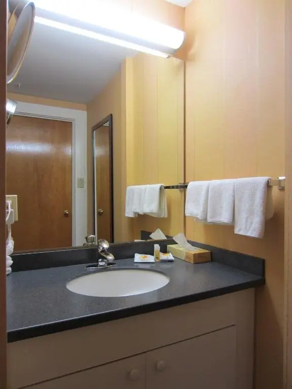 A Days Inn Vancouver Downtown bathroom with a sink, mirror and folded white towels