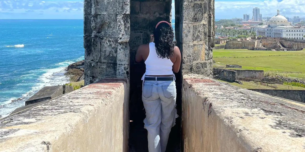 A visitor looking out to sea from inside a stone sentry box on a fort wall