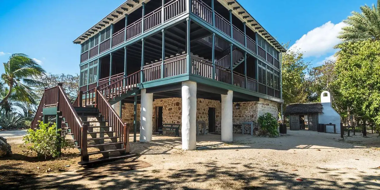 Pedro St. James, a three-storey stone house with wide wooden verandas and an outside staircase, under a blue sky