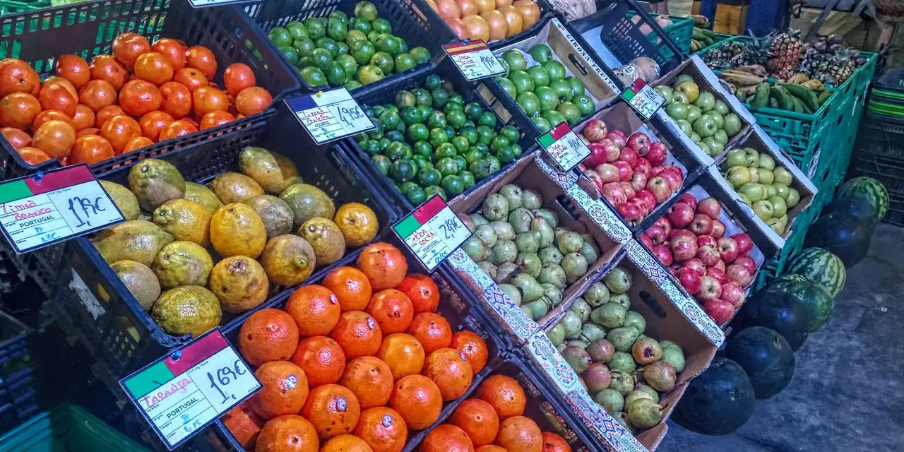 Market crates of tomatoes, oranges, passion fruit and limes with handwritten price cards