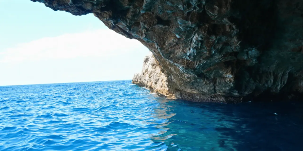 A rock arch over deep blue sea with open water beyond it