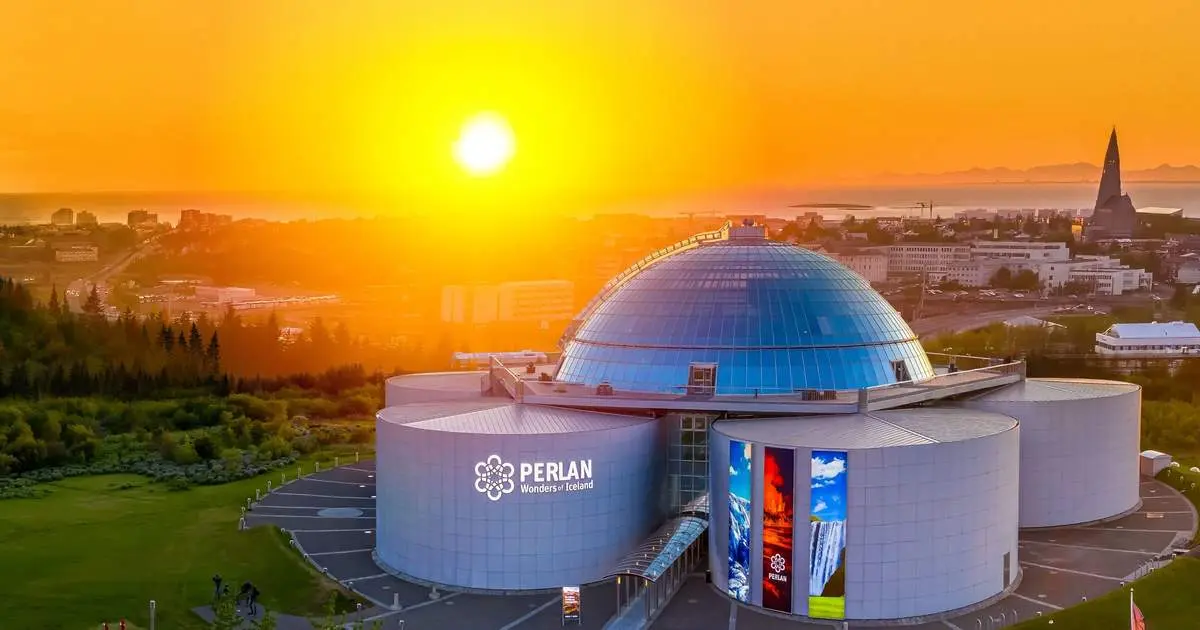 The glass-domed Perlan building at sunset with the Hallgrímskirkja tower in the distance