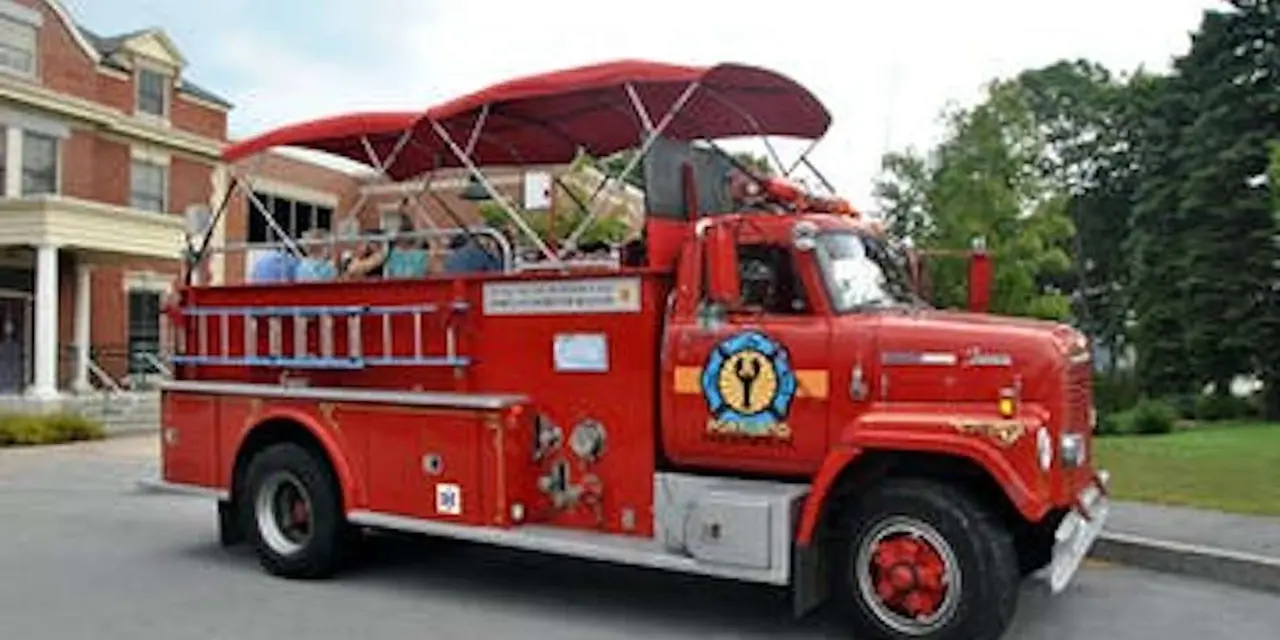 A red vintage fire engine with an open-air canopy of bench seats parked on a Portland street
