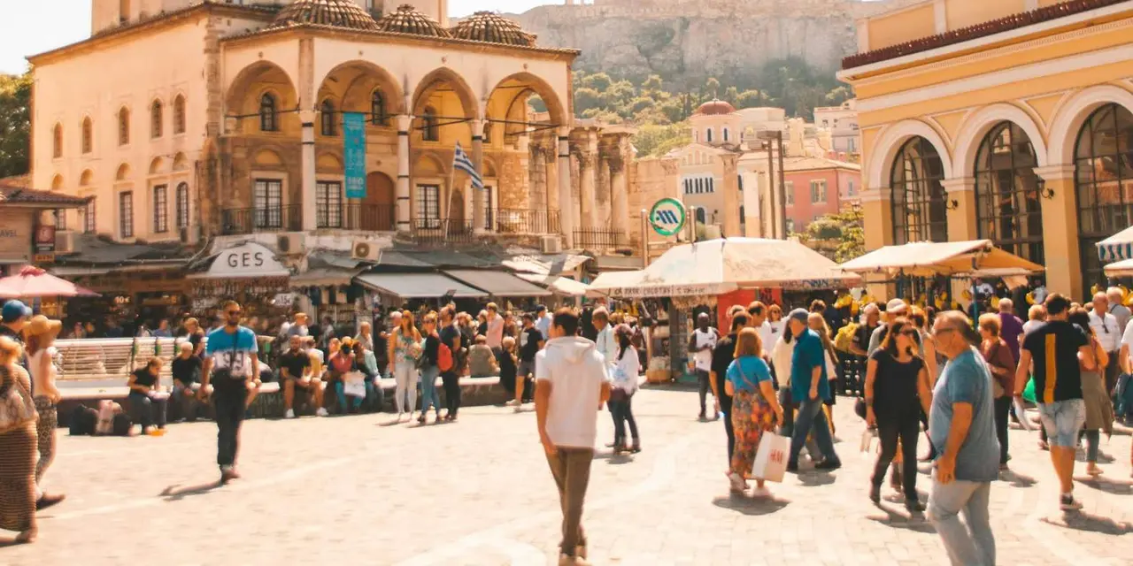 Monastiraki Square crowded with people and café umbrellas, the Acropolis on its hill behind