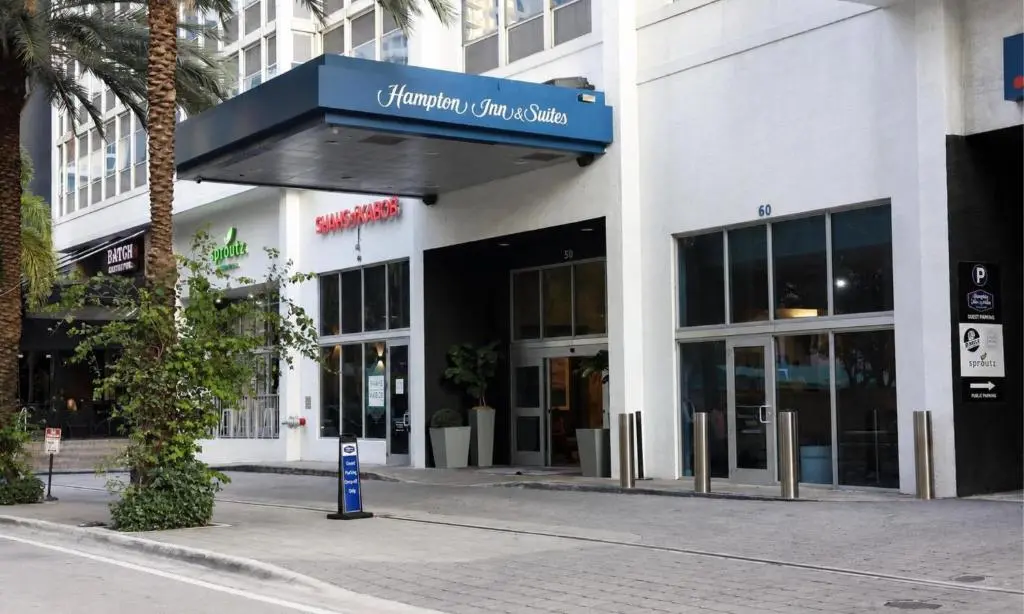 The Hampton Inn & Suites entrance canopy on a Brickell street, with a palm tree and the hotel's white tower above