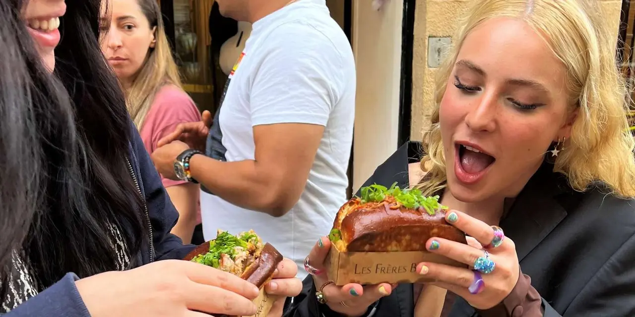 Tour guests holding burgers and snacks at a tasting stop, close up