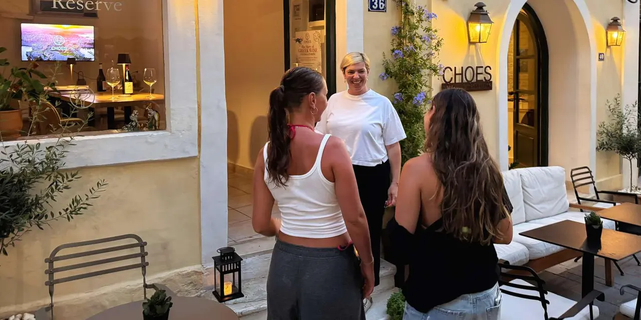 Guests standing outside the CHOES wine tasting room's arched doorway on an Old Town street