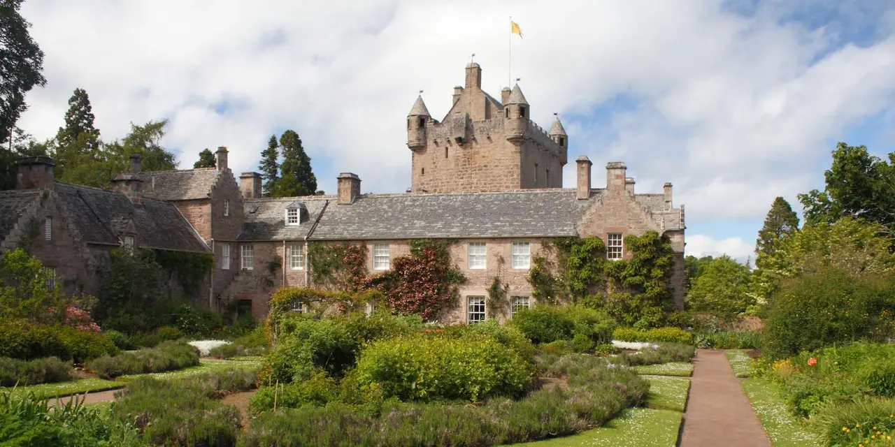 Cawdor Castle's tower behind its walled garden, with clipped lawns and flower beds in front