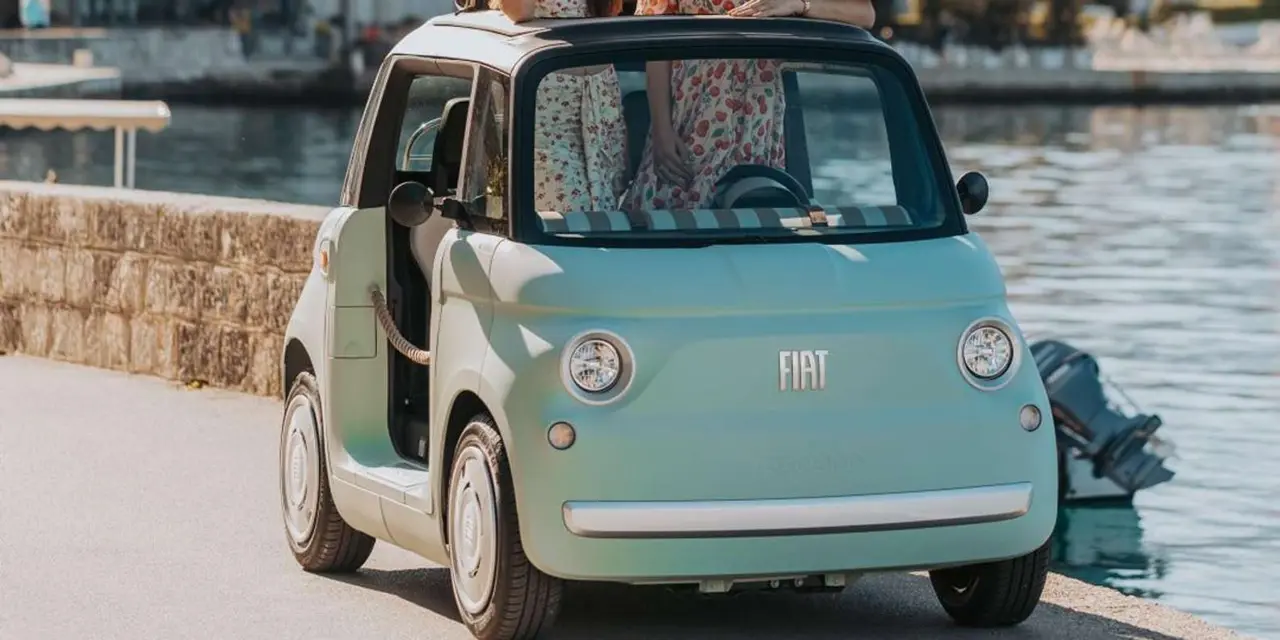 A pale green two-seat electric car parked beside the water on the Kotor waterfront